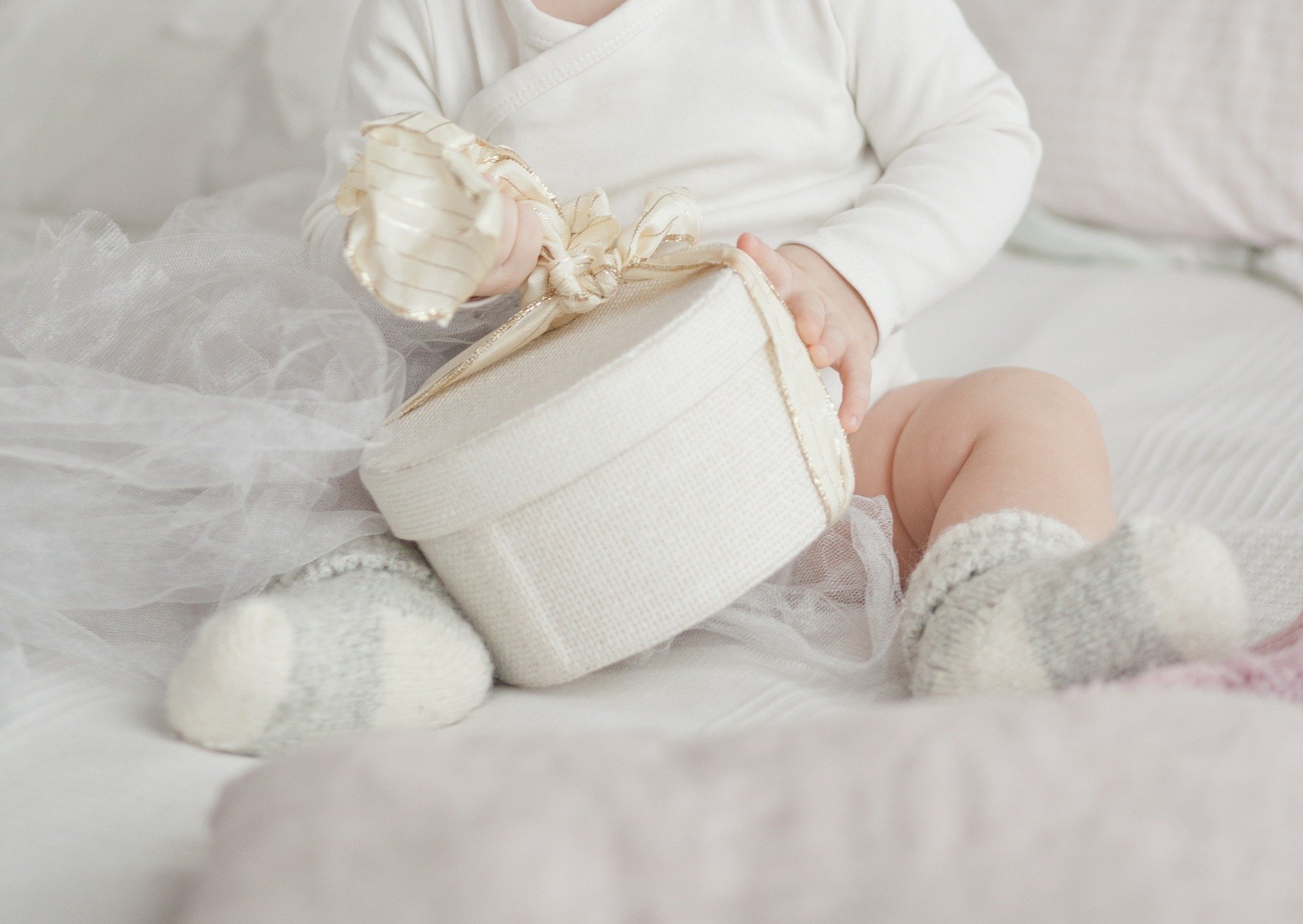 A baby holding a gift, unwrapping, minimalist holiday season, Christmas and New year, present