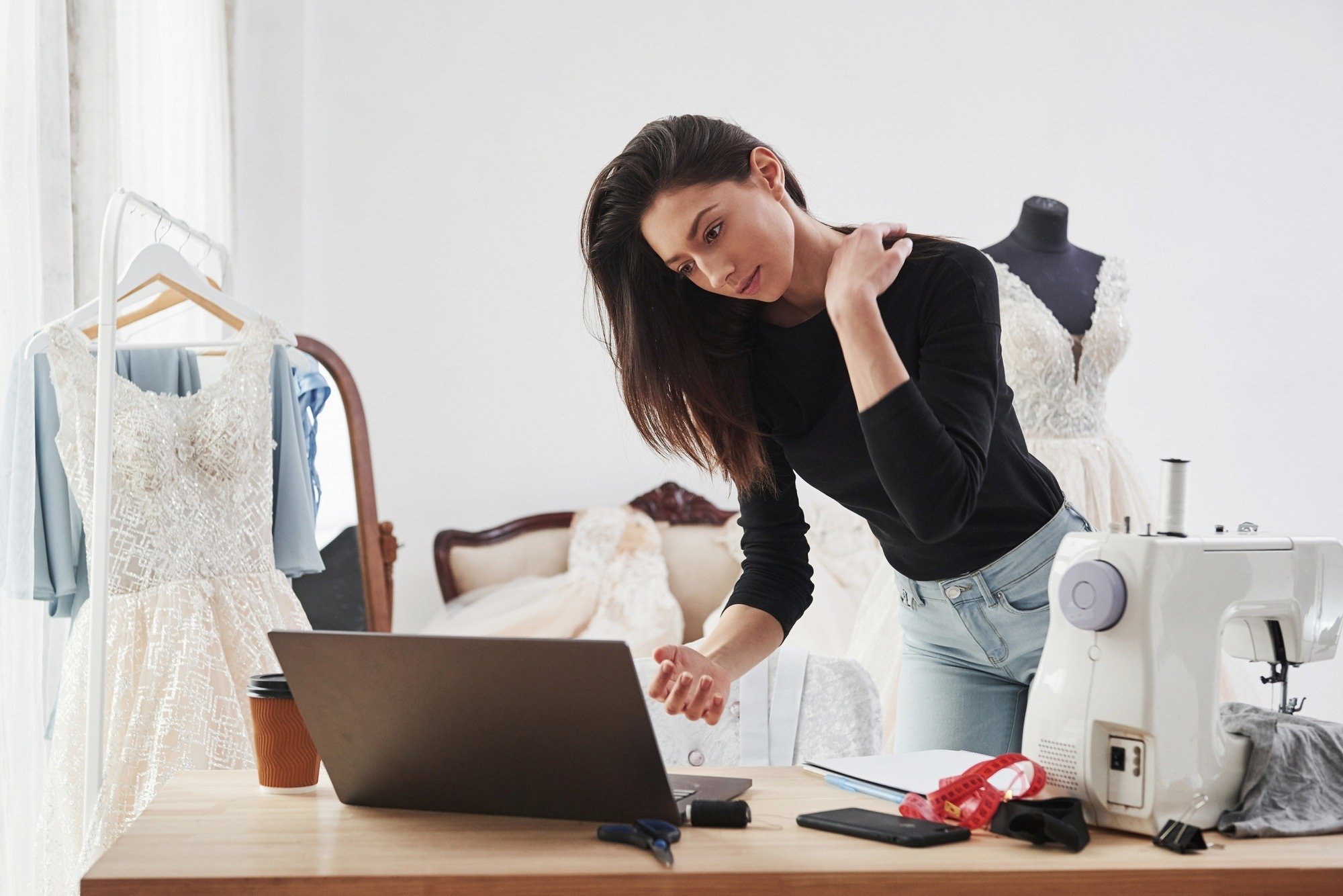 Using laptop. Female fashion designer works on the new clothes in the workshop